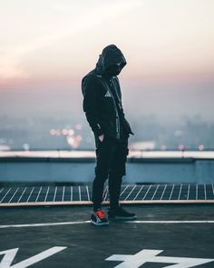 a man standing on top of a roof with his hands in his pockets and looking at the sky