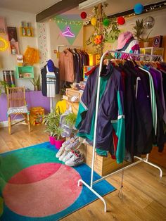 a clothing store filled with lots of clothes and shoes on display next to a colorful rug