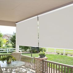 a covered patio with table and chairs on the back deck overlooking an open yard area