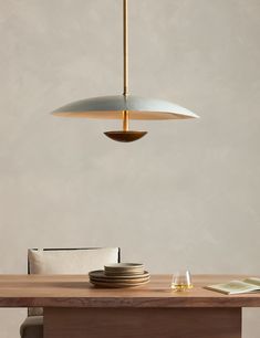 a wooden table with plates on it and a light fixture hanging over the dining room table