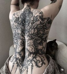 the back of a woman's body with tattoos on it