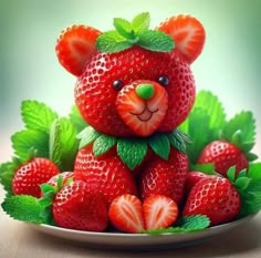 a teddy bear made out of strawberries sitting on top of a plate with green leaves