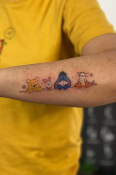 a person with a tattoo on their arm that has winnie the pooh characters on it