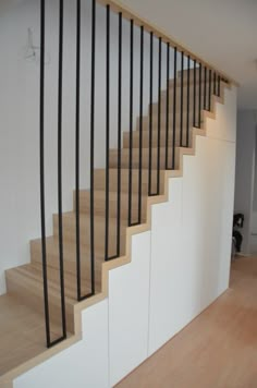 there is a wooden stair case with black railings on the top and bottom handrail