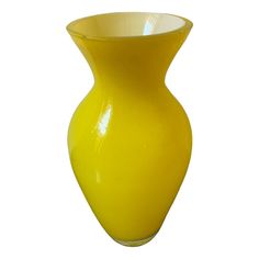 a yellow vase sitting on top of a white table