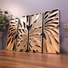 three wooden art pieces sitting on top of a table next to a potted plant