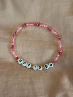 a pink beaded bracelet with the word hot on it and two white beads that say hot