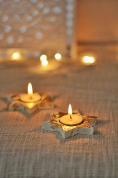 three lit candles sitting on top of a bed next to each other in front of a mirror