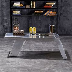 a metal table with books on it in front of a book shelf filled with books