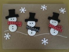 three snowmen with hats and scarfs on top of a piece of brown paper