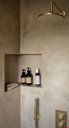 a bathroom with a shower head, soap and lotion bottles on the shelf next to it