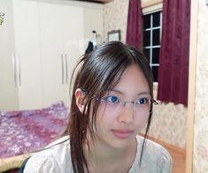 a girl with glasses is looking at the camera in her bedroom, while she's wearing eyeglasses