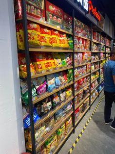 a man walking past a store filled with lots of food on display in front of shelves