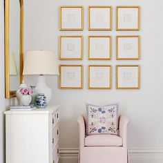 a living room filled with lots of framed pictures on the wall above a pink chair