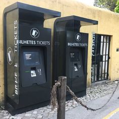 two black parking meters sitting next to each other on the side of a road near a building