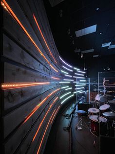 a room with some lights on the wall and drums in front of it at night