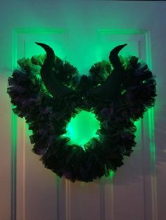 a wreath with horns is lit up in the dark by green light from behind it