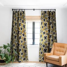 a chair sitting in front of a window next to a potted plant on top of a rug