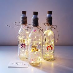 three glass bottles with fairy lights in them