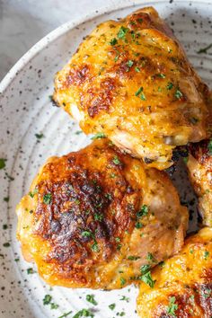 three pieces of chicken on a white plate with parsley sprinkled around it