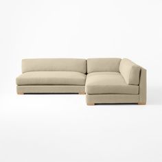 a beige sectional couch with wooden legs on a white background