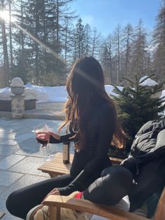 a woman sitting on top of a wooden bench next to a snow covered park area