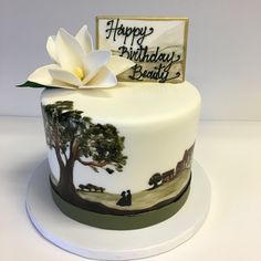 a decorated birthday cake with a white flower on top and a happy birthday sign in the middle