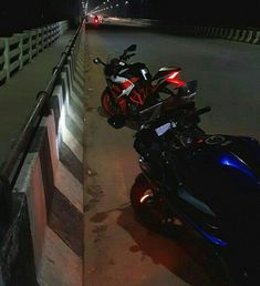 two motorcycles parked next to each other on the side of a road at night time