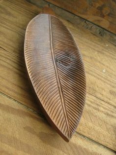 a wooden box with a leaf design on the lid sitting on top of a wood floor