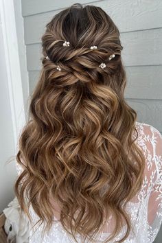 the back of a woman's head with long wavy hair and pearls in her hair