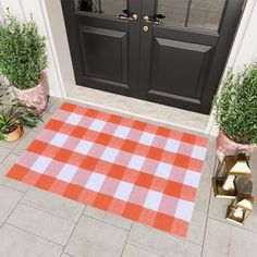 an orange and white checkered rug is on the front porch next to potted plants