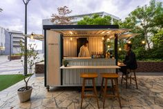 a man sitting at a table in front of a small bar with stools next to it