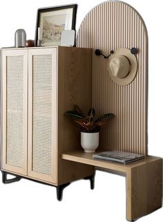 a wooden cabinet with a hat on top and a potted plant next to it