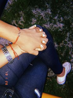 a woman sitting on top of a yellow bench wearing bracelets and holding her hands together