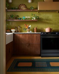 a kitchen with green tiled walls and wooden cabinetry, including a black stove top oven