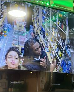 a man and woman are looking at a television screen in a grocery store, one is talking on the phone