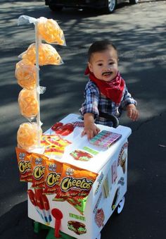 a young boy sitting on top of an ice cream cart filled with orange candies