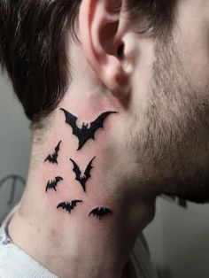 a man's neck tattoo with bats on his left side and behind the ear