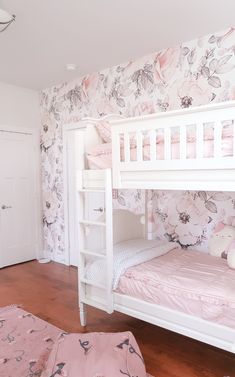 a white bunk bed sitting next to a pink rug on top of a wooden floor