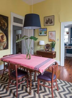 a dining room table with two chairs and a pink blanket on the rug in front of it