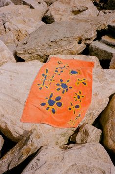 an orange towel laying on top of some rocks and stones with blue dots in the middle