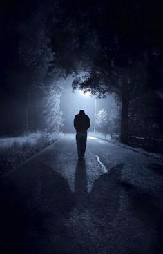 a person is walking down the road at night with their back turned to the camera