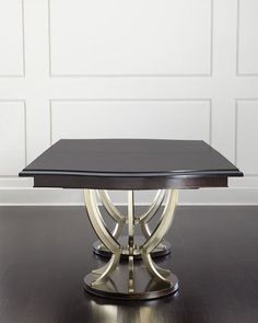 a black and silver table sitting on top of a hard wood floor next to a white wall