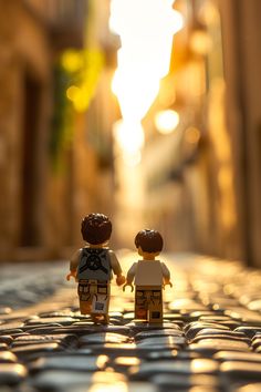 two legos are standing on the pavement in front of an alleyway at sunset