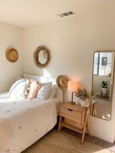 a bedroom with a bed, dresser and mirror in it's corner next to a window