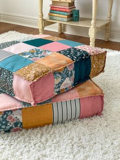 three patchwork pillows stacked on top of each other in front of a white rug