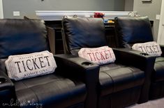 two black leather recliners sitting in front of a fireplace with movie tickets on them