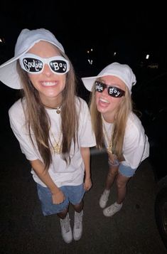 two girls wearing white hats and sunglasses are posing for the camera with their eyes covered