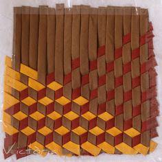 a piece of art made out of brown and orange squares on white paper with yellow edges