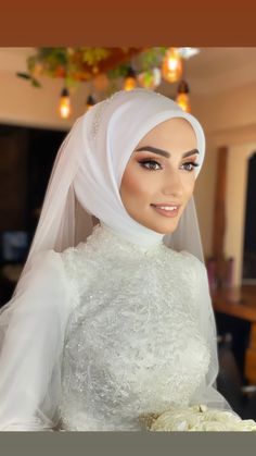 a woman wearing a white veil and holding a bouquet of flowers in her left hand